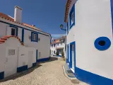Traditional white and blue houses in a small cobble stone alley in the historic center of Ericeira, Portugal.