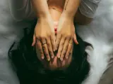 Una mujer se tapa la cara con las manos en señal de cansancio.