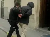 Un agente de la Policía Nacional custodia a uno de los detenidos.