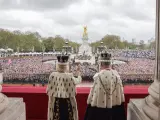 Los reyes Camilla y Carlos, de espaldas, saludan a su pueblo desde el balcón de Buckingham Palace.