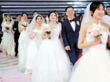 Noventa y nueve ex alumnos de la Universidad Oceánica de China celebran una ceremonia de boda en grupo en Qingdao, provincia de Shandong, China, el 8 de abril de 2023.
