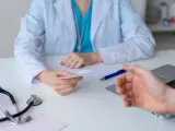 Una médico le da una receta a un paciente.