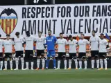 Los jugadores del Valencia posan con la pancarta de protesta de la afición del Valencia de fondo.