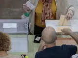 Una mujer deposita sus votos en las urnas habilitadas en un colegio electoral de Valencia para las elecciones municipales y autonómicas.