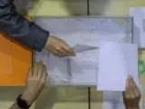 Un hombre deposita su voto en una urna en un colegio electoral de Valencia.
