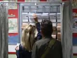 Votantes eligen las papeletas para votar en un colegio electoral.
