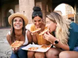 Turistas probando la pizza al taglio en Roma.