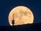 La luna emerge tras una torre de telecomunicaciones vista desde Matraverebely, en Hungría.