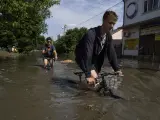 Los residentes locales intentan andar en bicicleta a lo largo de una carretera inundada despu&eacute;s de que la represa Kakhovka explotara durante la noche, en Kherson, Ucrania.