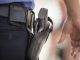 Un agente de policía, con la mano cerca de su arma reglamentaria.