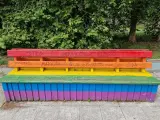 Pintadas homófobas en un banco pintado con la bandera arcoiris.