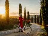 Cute girl in red dress watching the sunset sitting on a vintage bicycle