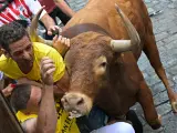 Un toro embiste a un grupo de corredores durante el tercer encierro de los sanfermines 2023, este domingo en Pamplona.