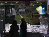 Una pescadera atiende a una clienta en una pescadería de un mercado madrileño.