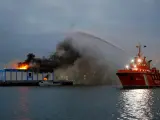 Equipos de bomberos combaten por mar y tierra un incendio en una nave frigorífica en puerto de Las Palmas.