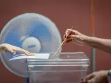 Una votante introduce el sobre en la urna en las elecciones generales ante un ventilador este domingo en el Teatro Rojas de Toledo.