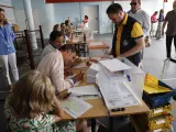 Un cartero que lleva votos por correo entrega las papeletas en una de las mesas en un colegio electoral de Madrid este domingo.