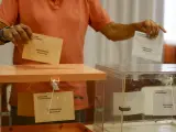 Una persona, ante una urna en un colegio electoral.
