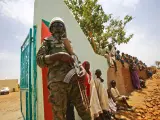 A UN peacekeeper stands guard as crowds of children and villagers gather to welcome Steven Koutsis (unseen), the United States' top envoy in Sudan, in the war-torn town of Golo in the thickly forested mountainous area of Jebel Marra in central Darfur on June 19, 2017. The town was a former rebel bastion which was recently captured by Sudanese government forces. The top US envoy in Sudan began a four-day trip to Darfur on June 18, 2017 to assess security in the war-torn region as the UN prepares to downsize its 17,000-strong peacekeeping force. His visit also comes just weeks before President Donald Trump's administration decides whether to permanently lift a two-decades old US trade embargo on Sudan. / AFP PHOTO / ASHRAF SHAZLY (Photo credit should read ASHRAF SHAZLY/AFP via Getty Images)