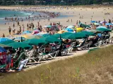 Varias personas se refugian del sol bajo sombrillas en Pontevedra.