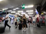 Un grupo de personas con maletas camina por uno de los pasillos de la estación de Atocha-Almudena Grandes