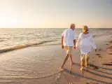 Una pareja de jubilados pasea por la orilla de una playa