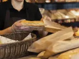 Cliente en un supermercado con una barra de pan.