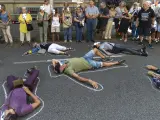 Varias personas se tumban sobre siluetas de tiza en el suelo como si fueran algunas de las víctimas de los atentados durante una concentración convocada por la plataforma 17A.
