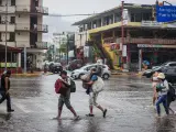 Personas caminan por una calle encharcada debido a las fuertes lluvias en el balneario de Acapulco, México.