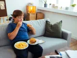 Un niño con sobrepeso comiendo hamburguesas y patatas fritas