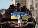 Una mujer sostiene la bandera frente a blindados rusos incautados por el ejército ucraniano