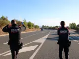 Dos mossos en la carretera T-310, cortada por el incendio.