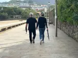 Una pareja pasea por un paseo marítimo en Bizkaia pertrechados de paraguas.
