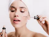 Mujer aplicando corrector de maquillaje en sus ojeras.