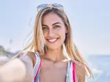 Joven rubia sonriendo feliz haciendo selfie junto al teléfono inteligente en la playa
