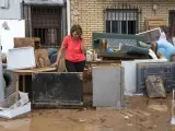 Una persona junto a los objetos de una vivienda inundada, en Buenache de Alarcón, Cuenca.