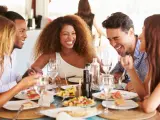 Grupo de jóvenes amigas disfrutando de comida en el restaurante al aire libre riendo