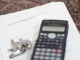 Una calculadora y unas llaves sobre un contrato de arrendamiento (alquiler) de una habitación en una vivienda compartida.
