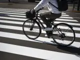 Un ciclista cruza un paso de cebra con su bicicleta