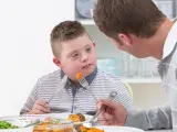 Un padre dando de comer a su hijo.