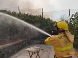 Un operario del Cabildo de Tenerife refresca terrenos en la reactivación del incendio en Tenerife.