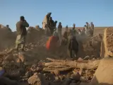 Afectados por los terremotos de Afganistán caminan sobre los restos de sus viviendas en la provincia de Herat.