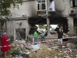 Civiles israelíes inspeccionan los edificios residenciales tras el impacto de un misil.