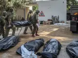 Los soldados israelíes envuelven los cuerpos de los asesinados en el kibutz Kfar Aza.
