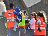 Voluntarios de la Cruz Roja reciben a migrantes al pisar tierra en la isla canaria de El Hierro.