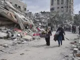 Mujeres palestinas junto a edificios destruidos por ataques aéreos israelíes en Nuseirat, en Gaza.