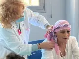 Begoña Navarro coloca un pañuelo a Carmela Martín, paciente oncológica, durante el taller de estética en el Hospital de Móstooles.