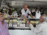 Varios clientes compran queso en un puesto en un mercado de abastos.