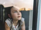 Una niña mirando por la ventana, en una imagen de archivo.
