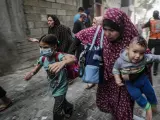 Una mujer huye con dos niños de un ataque aéreo israelí en la ciudad de Gaza, el 23 de octubre de 2023.